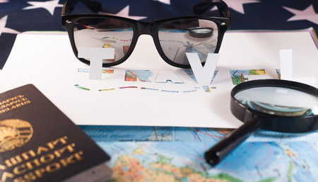 The concept of travel, passport, glasses, magnifying glass,stencil, paper, map of the world on the American flagの写真素材