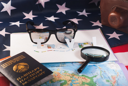 The concept of travel, passport, glasses, magnifying glass,stencil, paper, map of the world on the American flagの写真素材