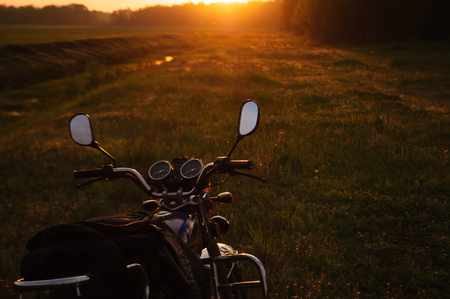 classic motorcycle at sunset, on a grass background, the journey on a motorcycleの写真素材