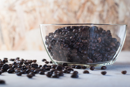 Coffee beans scattered on the table, coffee in a glass bowl, pattern for coffee commercialの写真素材