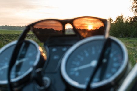 Sunglasses on the speedometer motorcycle, sunset through sunglassesの写真素材
