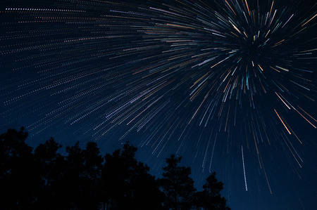 Beautiful night sky beautiful stars swirl above the trees, star trail vortexの写真素材