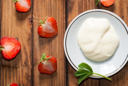 Strawberries with whipped cream, delicious dessert on wooden background, green leavesの写真素材
