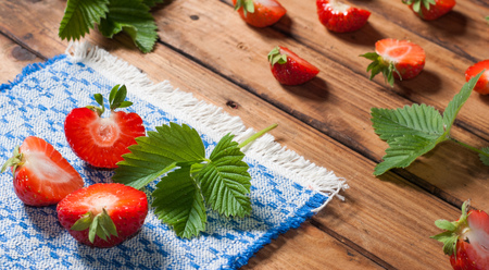 Sliced strawberries with leaves and sprigs of mint, embroidered napkin, of wooden backgroundの写真素材