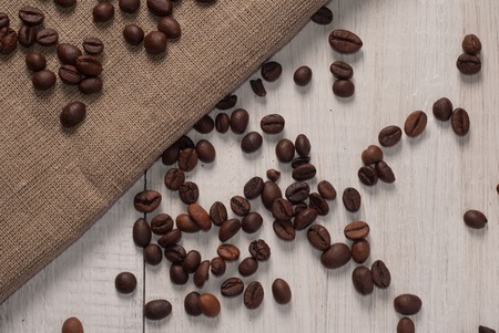 coffee beans on wooden background and rough cloth, top viewの写真素材