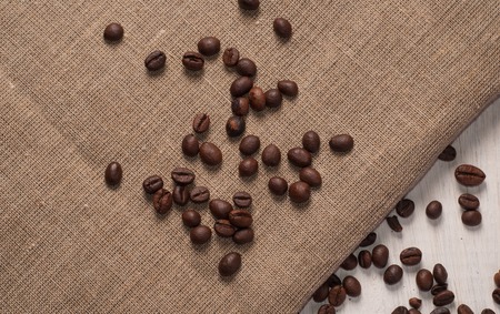 coffee beans on wooden background and rough cloth, top viewの写真素材
