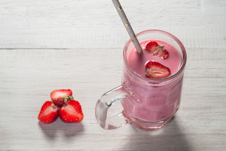 Strawberry milkshake in glass goblet with handle, straw from paper with stars, a smoothie with strawberriesの写真素材