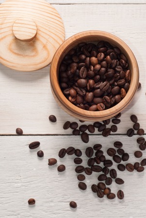 A wooden bowl with coffee beans on old wooden table, top viewの写真素材