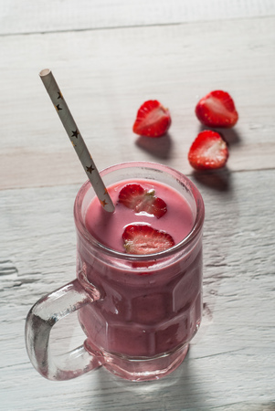 Strawberry smoothie in glass jar with handle, old wooden table. cut strawberries white backgroundの写真素材