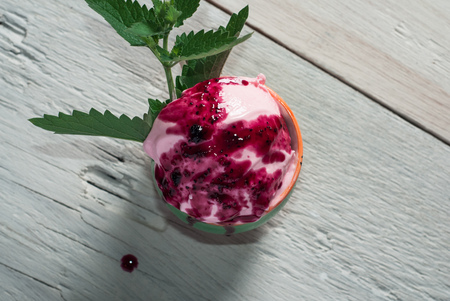 Homemade rose ice cream and a sprig of mint in a Cup, the dessert a rustic, wooden background, top viewの写真素材
