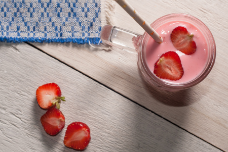 Strawberry milkshake in glass goblet with handle, straw from paper with stars, a smoothie with strawberriesの写真素材