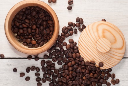 A wooden bowl with coffee beans on old wooden table, top viewの写真素材