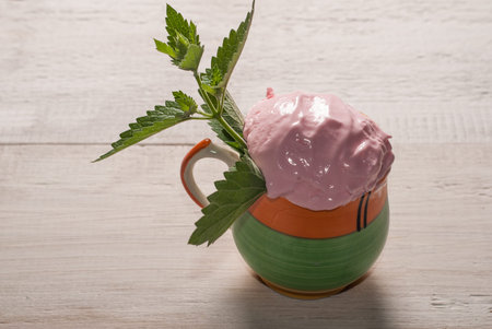 Homemade Strawberry ice cream in a Cup and mint. white wooden background