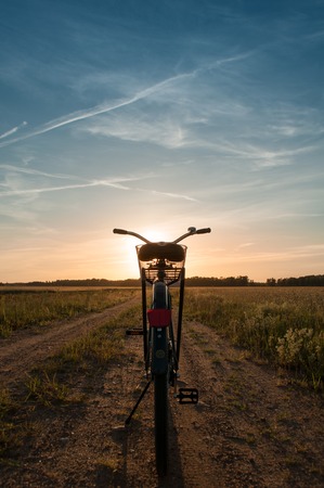 Bike at sunset, Blue sky with clouds and green field along a rural road, Bicycle on the bandwagonの写真素材