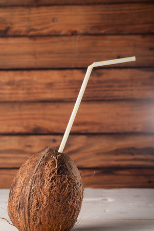 peeled coconut with drinking straw on wooden tableの写真素材