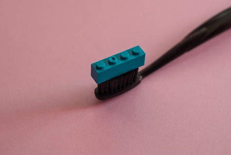 black toothbrush and toy block, on a pink background. minimal style. surreal photographyの写真素材