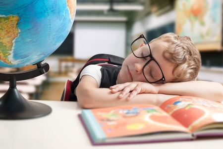 The little boy fell asleep in class, the nerd is asleep at his Deskの写真素材