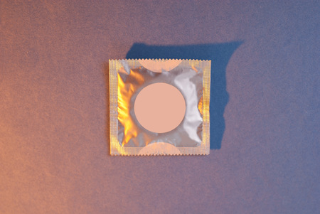 A condom on a colored paper background.the prevention of AIDS. the means of Contraceptionの写真素材