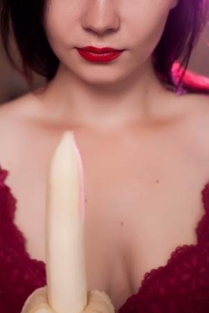 Sexy girl in red bra holding a banana, red lipstick, conception oral sexの写真素材