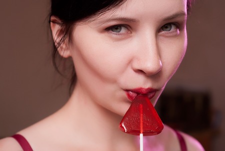 Nice girl licks Lollipop, the concept of seduction, close-up portraitの写真素材