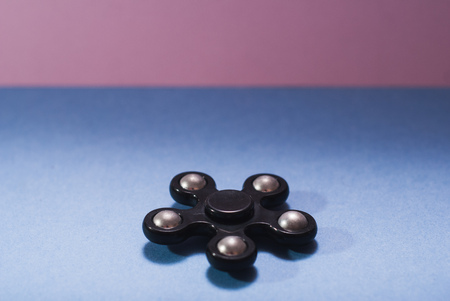 Fidget spinner black, gadget to relieve stress. blue and pink background.の写真素材