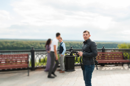 Handsome young man with digital camera while standing outdoors. the concept of a profession photographerの写真素材