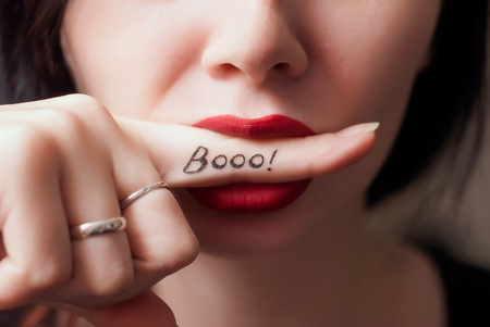 Portrait of sensual young woman with red lips , finger in mouth, close-up, the inscription on the finger Boo, creative banner for Halloweenの写真素材