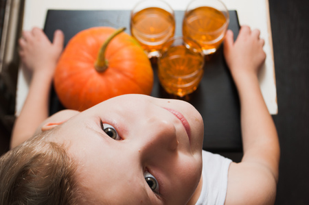 A little boy carrying a tray with pumpkin and drinks , a Halloween party,の写真素材