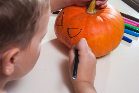 Child draws a face on the pumpkin, make Jack-o'-lantern before Halloween, top viewの写真素材