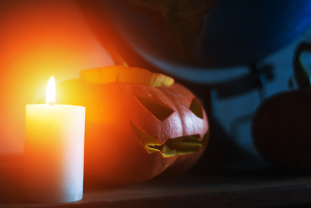 Halloween-scary pumpkin and burning candle on the background of the globeの写真素材