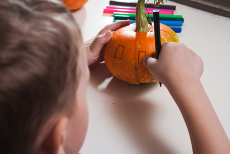Jack-o-lantern DIY. the boy draws a face on the pumpkin. preparing for the Halloween partyの写真素材