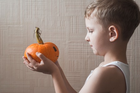 The child looks at the Jack-o-lantern, Little boy standing with pumpkin in handsの写真素材
