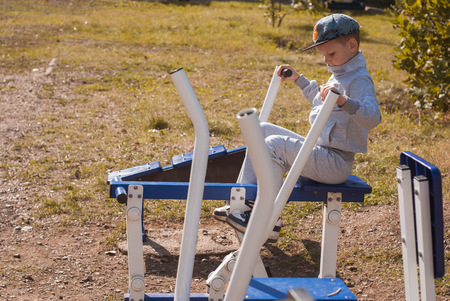 The little boy is on the power trainer on a Sunny day, healthy lifestyle, strong kid, young athleteの写真素材