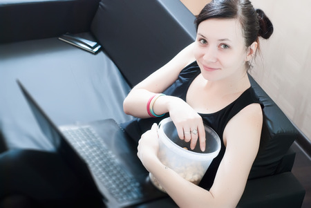 Girl distracted from watching series, movies and popcornの写真素材
