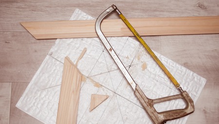an old hacksaw blade with a yellow, wooden material for repair work, small shavings and sawdust on white backgroundの写真素材