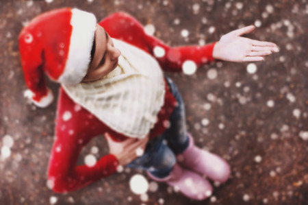 The girl in the Santa hat, Pretty young woman catching snowflakes. Christmas snowfallの写真素材