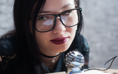 Cute girl in glasses conducts a podcast, closeup portrait of the girlの写真素材