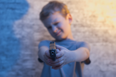 the boy with the gun pointing, selective focus on the barrel of the gun, the concept of bad parentingの写真素材