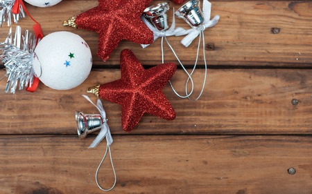 Christmas background with festive decorations on a dark wooden Board, the composition of the Christmas baubles, red star, silver bells and white ballの写真素材