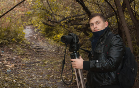 Young photographer with camera and tripod in the fall.