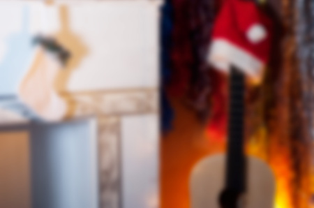 Abstract Christmas blurred background, an acoustic guitar in a Santa hat and a white fireplace with stockingの写真素材
