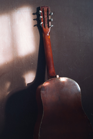 acoustic guitar at a wall, grunge background. the light from the windowの写真素材
