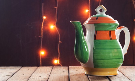 The teapot stands on a wooden table. In the background is a festive illumination. The concept of a Christmas tea party. Template for advertisingの写真素材