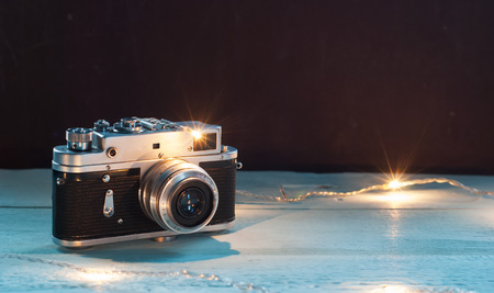 Old vintage camera on wooden planks and Christmas garlandの写真素材