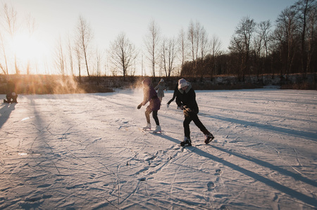 Teenagers frolic on the ice at sunset, winter fun girl skatingの写真素材
