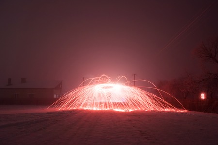 Bright crimson sparks in fog, steel wool photography, beautiful sight in winter nightの写真素材
