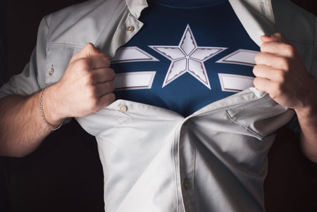 Superhero Tears off his Shirt on a dark Background. Tearing the shirt on his chest. The star on his...