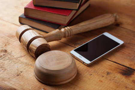 smartphone, the judge's gavel on wooden background. Digital gadget. Illegal access to computer...