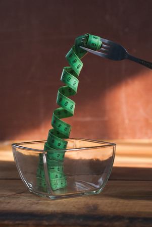 Measuring tape on the fork, the image of the concept of diet, the symbol of a slender figureの写真素材