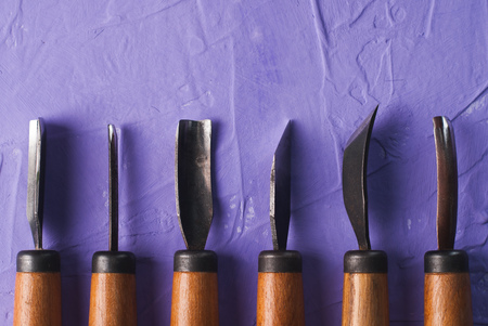 Tools for wood carving on a purple textured background, top view cutters, craft toolsの写真素材